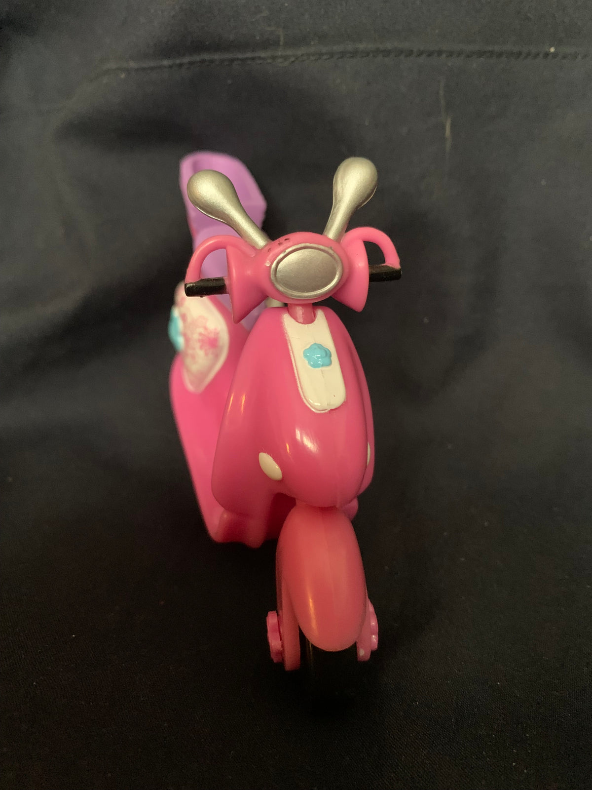 Pink plastic scooter toy with silver handlebars and white panel featuring a blue cloud design from toys 001