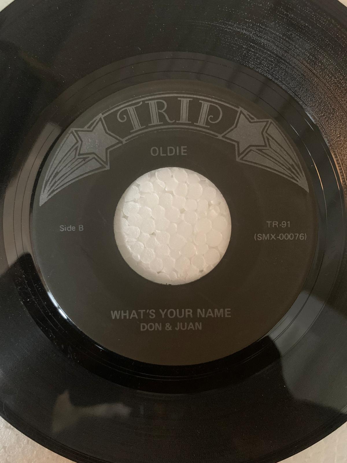 Black vinyl record with silver embossed label and star designs featuring what’s your name by don and juan