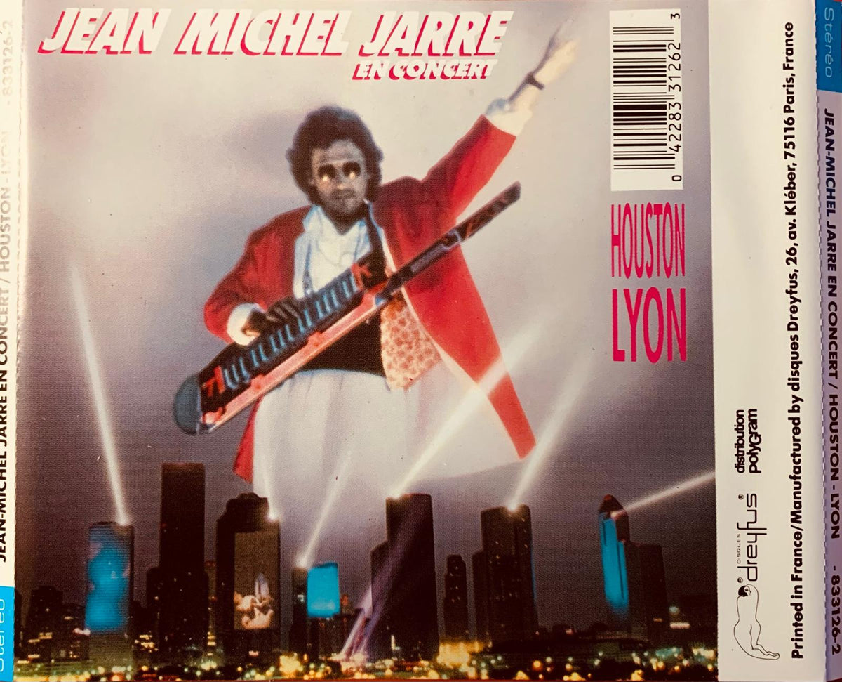 Jean Michel Jarre en concert cassette tape cover with vibrant red jacket and white pants against city skyline backdrop
