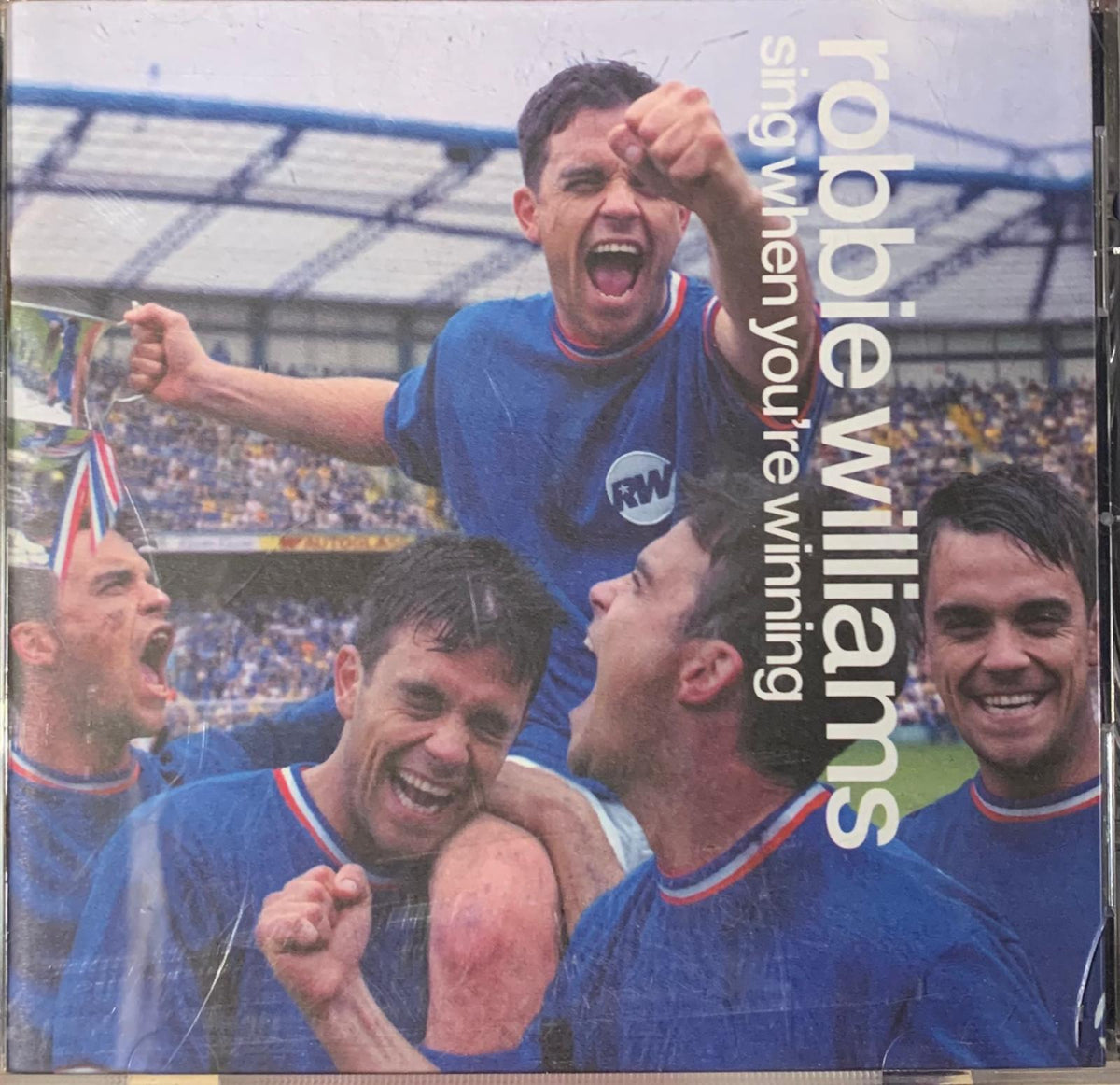 Robbie Williams sing when you’re winning original cd cover with artist in blue football jersey with red and white trim