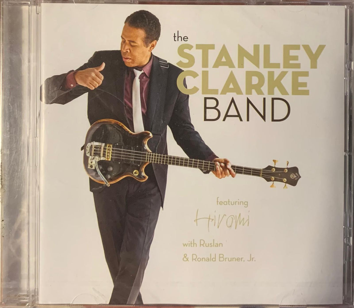 Black and gold electric bass guitar with glossy finish held by musician in formal attire for stanley clarke band cd