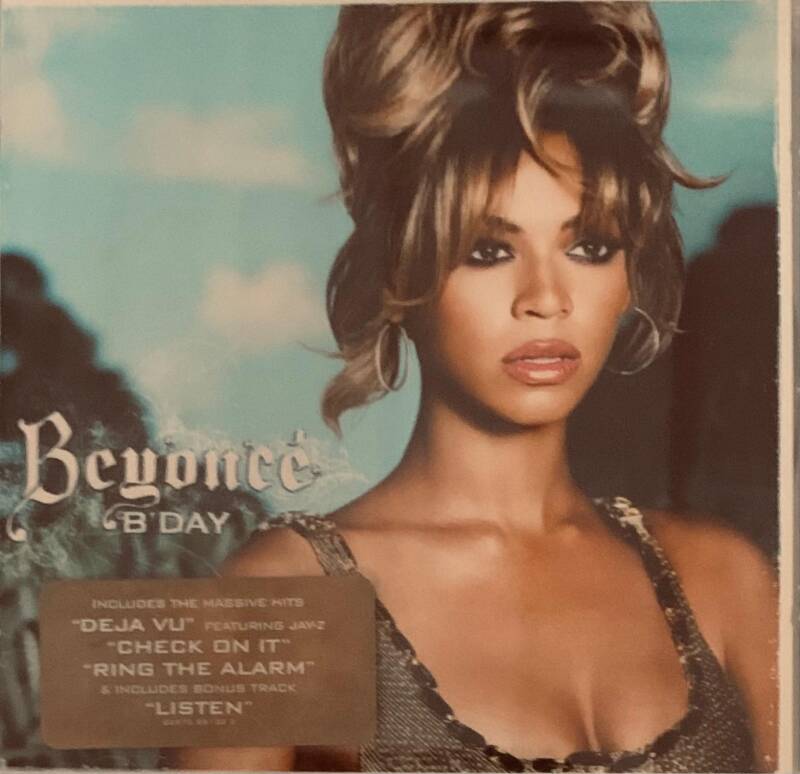 Beyoncé bday CD cover featuring her in a black sequined top with voluminous blonde and brown hair against teal sky