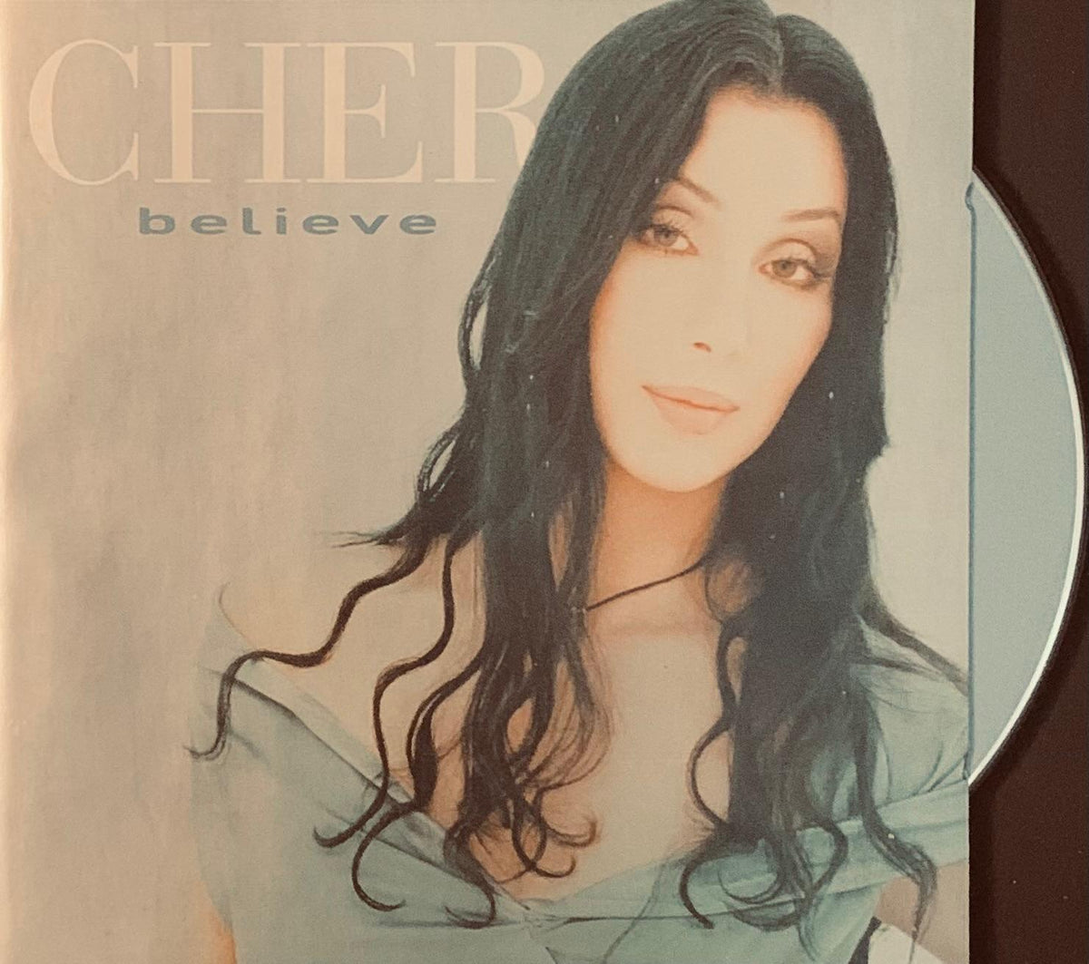 Cher believe 1998 original cd album cover with portrait of singer with long dark hair on muted beige background