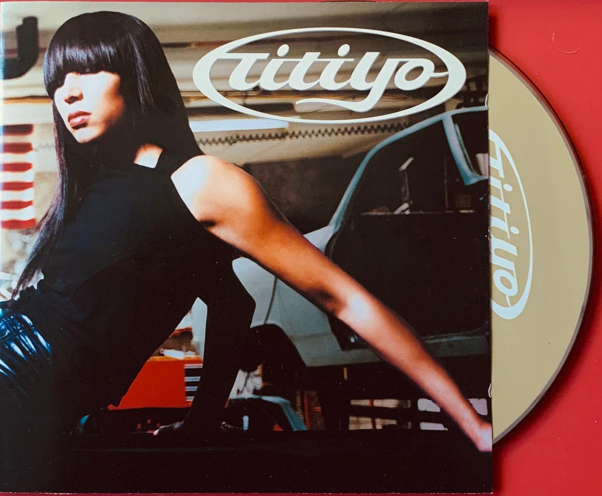 The album cover for Titiyo features a woman with long black hair wearing a sleek black sleeveless top