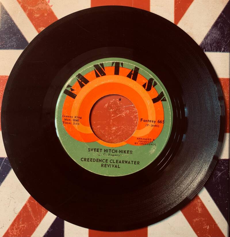 Black vinyl 7 inch record with colorful orange green red label featuring sweet hitch hiker by creedence clearwater revival