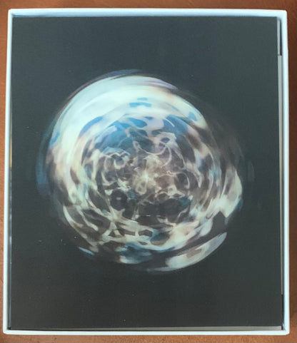 A swirling translucent glass orb with intricate blue and white patterns from punk floyd endless summer collection