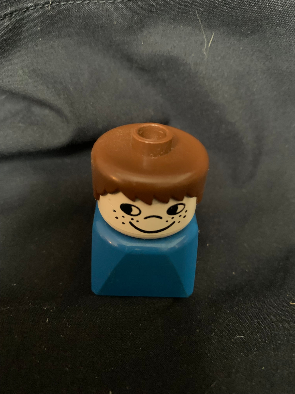Lego minifigure toy with brown hair smiling head and blue torso from toys 001 collection