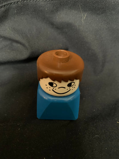Lego minifigure toy with brown hair smiling head and blue torso from toys 001 collection