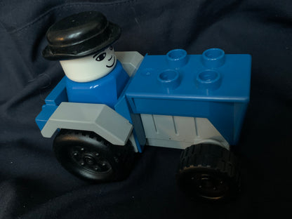 Blue and gray lego-style tractor toy with black hat minifigure driver in toys 001 product set