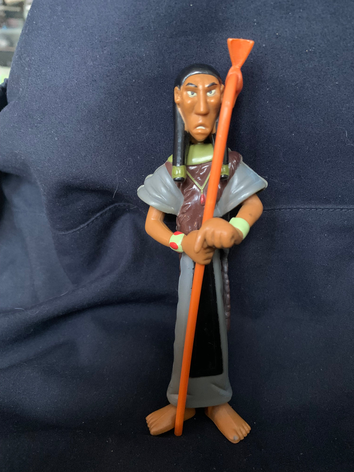 A plastic figurine from Toys 001 featuring a dark-skinned character with braided hair and an orange staff