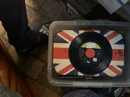 Soul 7 inch black vinyl record with red center label on union jack surface inside clear plastic storage bin