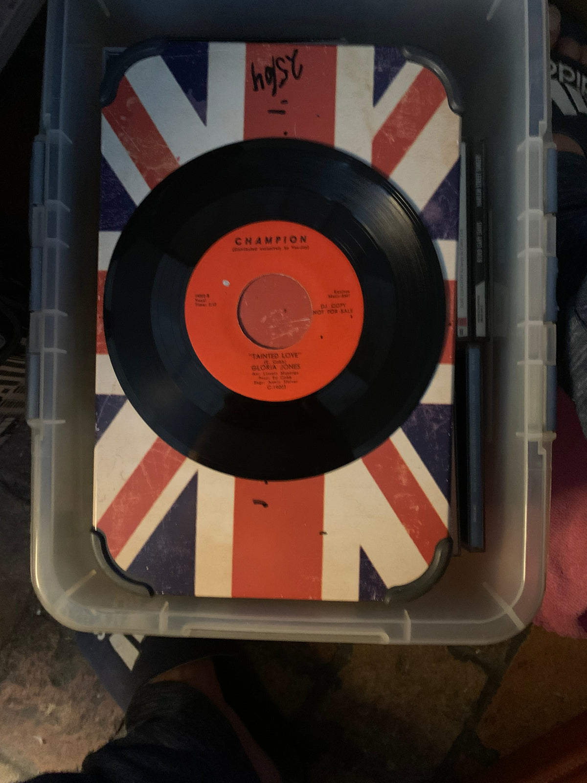 Black vinyl record with orange champion label on union jack surface inside clear plastic container for soul 7 product