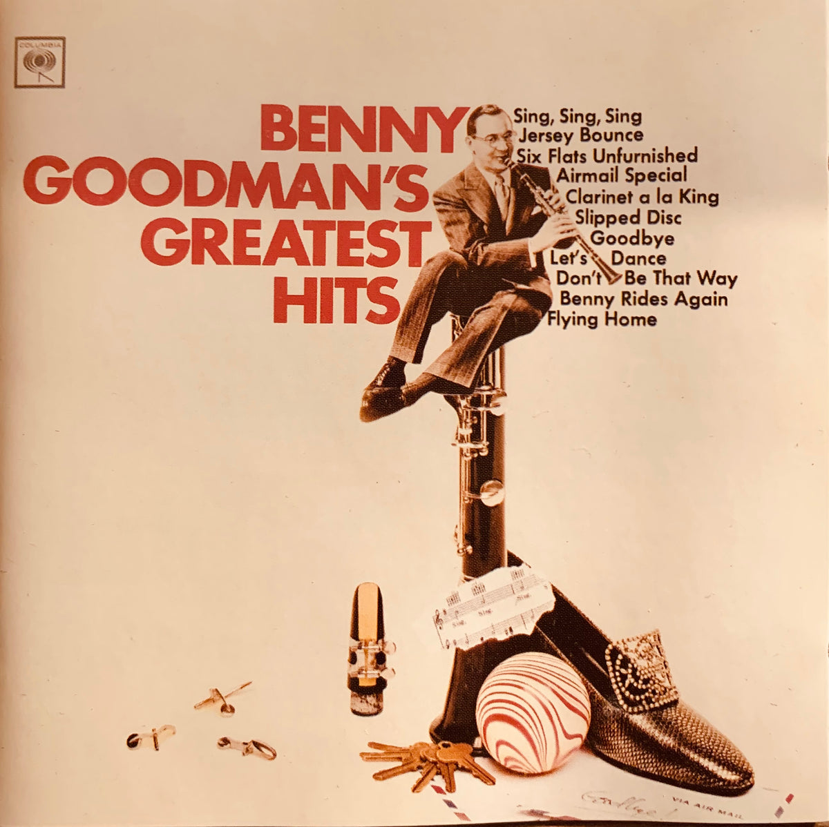 Benny Goodman sits on a tall dark wooden clarinet surrounded by musical accessories on the CD 001 greatest hits cover