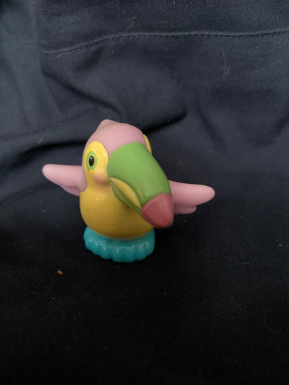 A colorful plastic toucan toy with a green beak pink wings and head yellow body and teal base from toys 001
