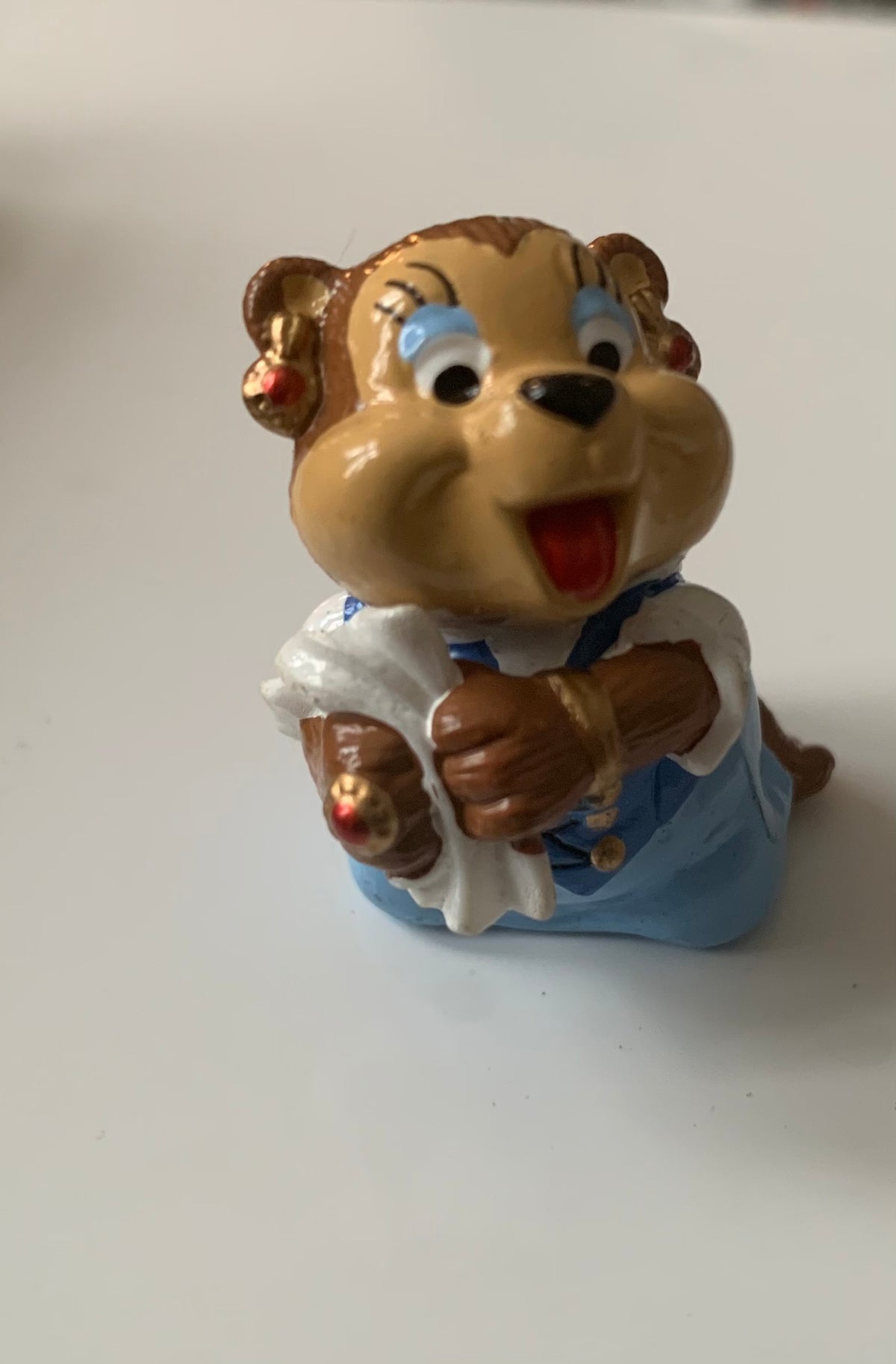 A cheerful brown monkey figurine with blue eyes and red tongue wearing white shirt and blue overalls from figurines dragon