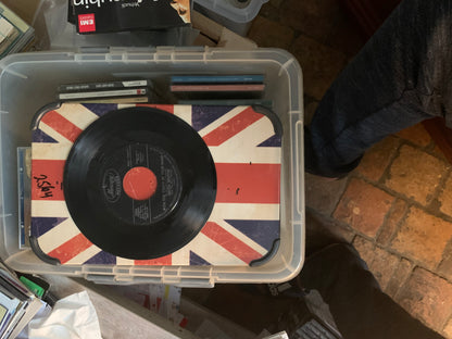 Black vinyl record soul 7 with red center label on union jack mat inside clear plastic storage bin