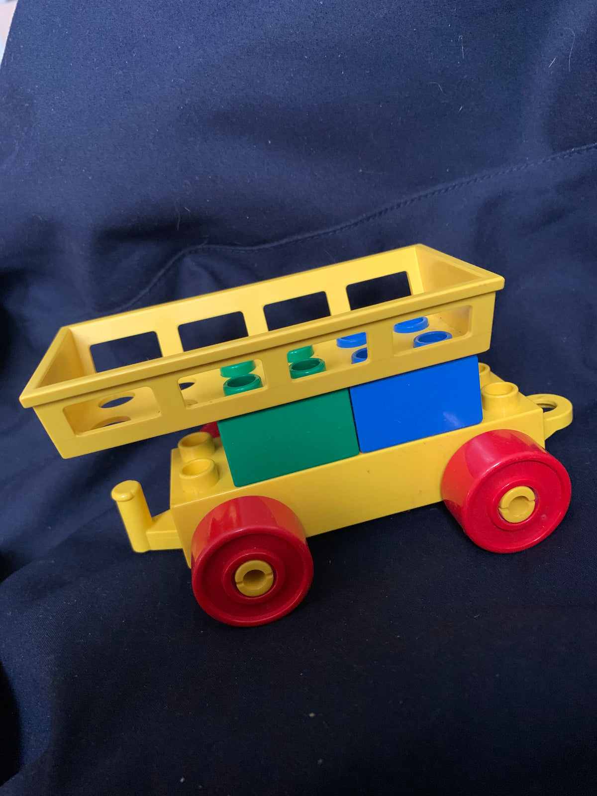 Yellow plastic duplo train car with red wheels and blue green cargo section from toys 001 product line