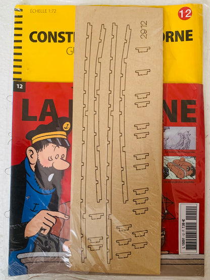 A beige cardboard sheet with laser-cut wooden train track pieces and a station platform in clear plastic packaging for la licorne