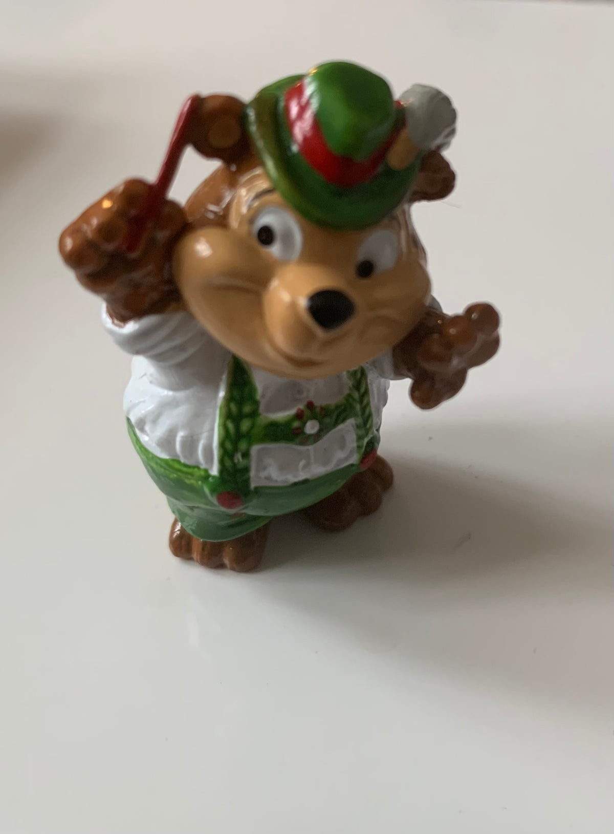 A brown cartoon mouse figurine wearing a green hat with red trim white shirt and green overalls from figurines dragon
