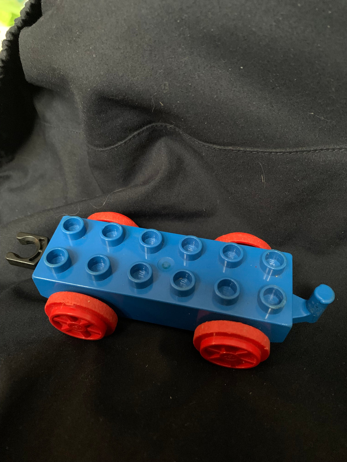 Blue plastic lego train car with red wheels and small hook for connecting toy train cars in toys 001