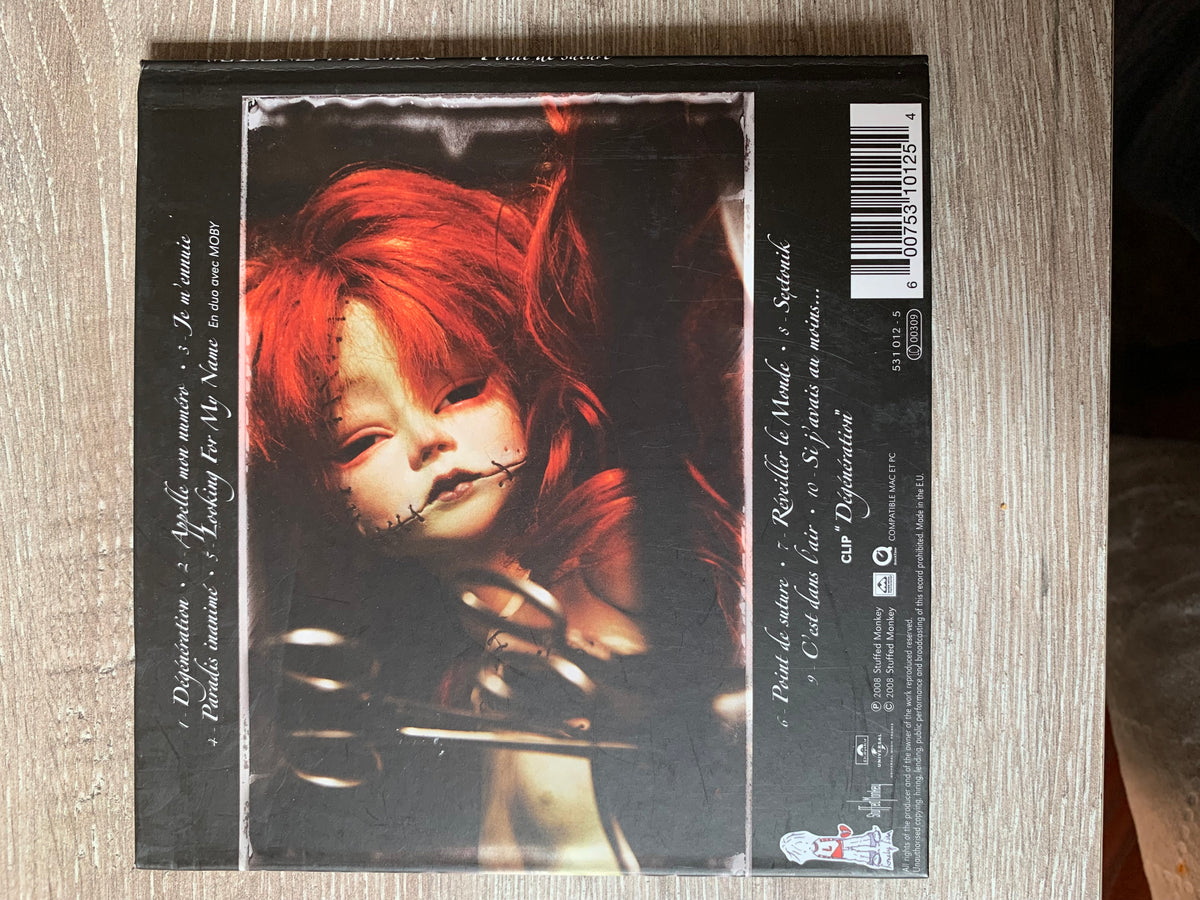 Black cd case titled CD 001 featuring a haunting doll with vibrant red hair and stitched facial features on dark background