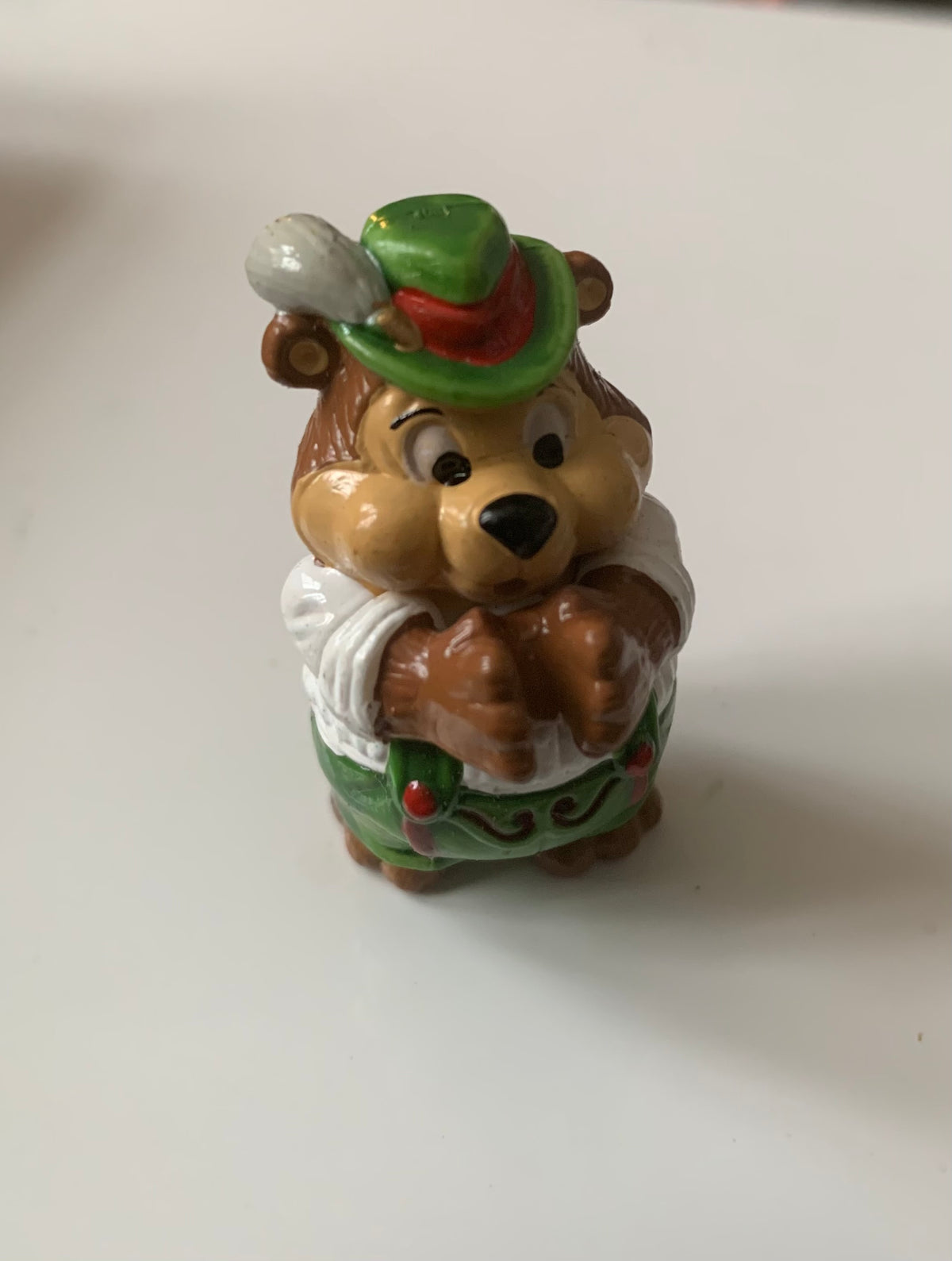 A charming brown bear figurine in green hat red trim white shirt and green shorts with red berries from figurines dragon