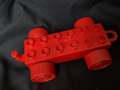 Red plastic duplo toy car with four wheels and a handle in toys 001 product image