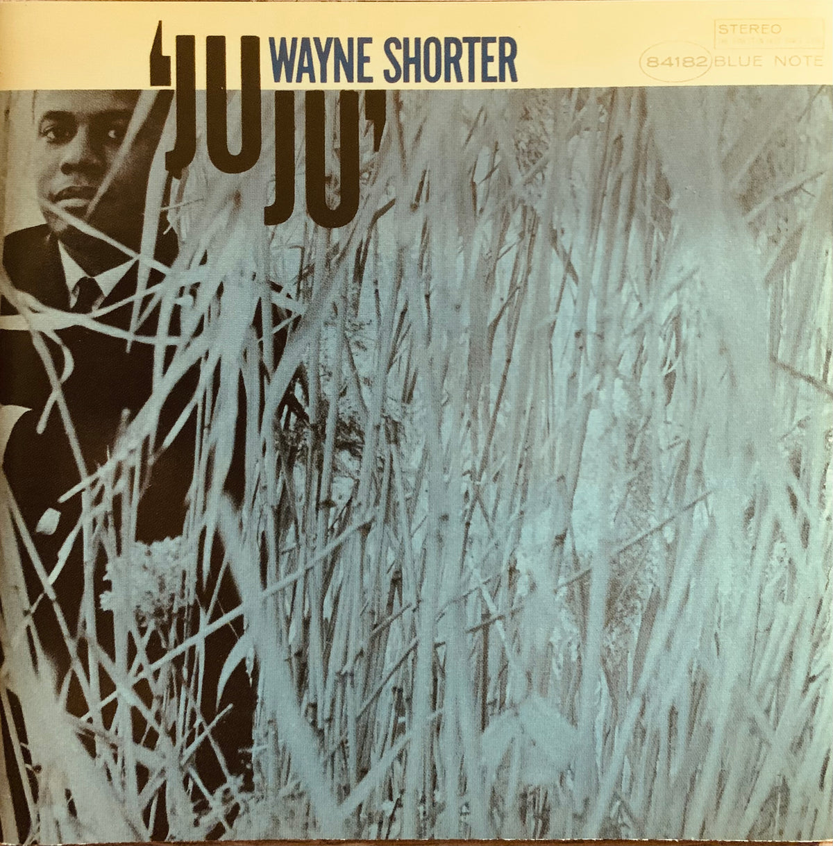 Wayne shorter juju cd 001 album cover with black and white photo of artist partially obscured by tall grass on beige background