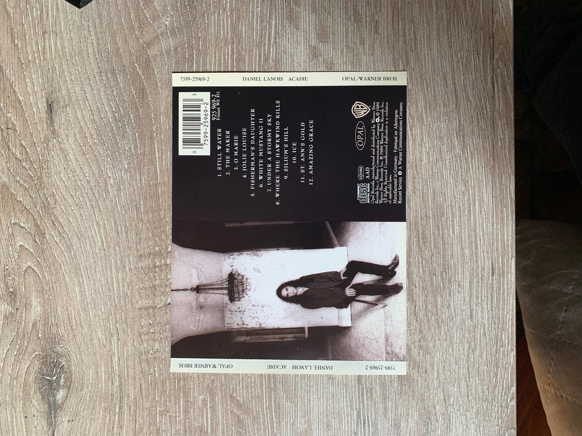 Black and white album cover for acadie by daniel lanois featuring the artist sitting on steps cd 001