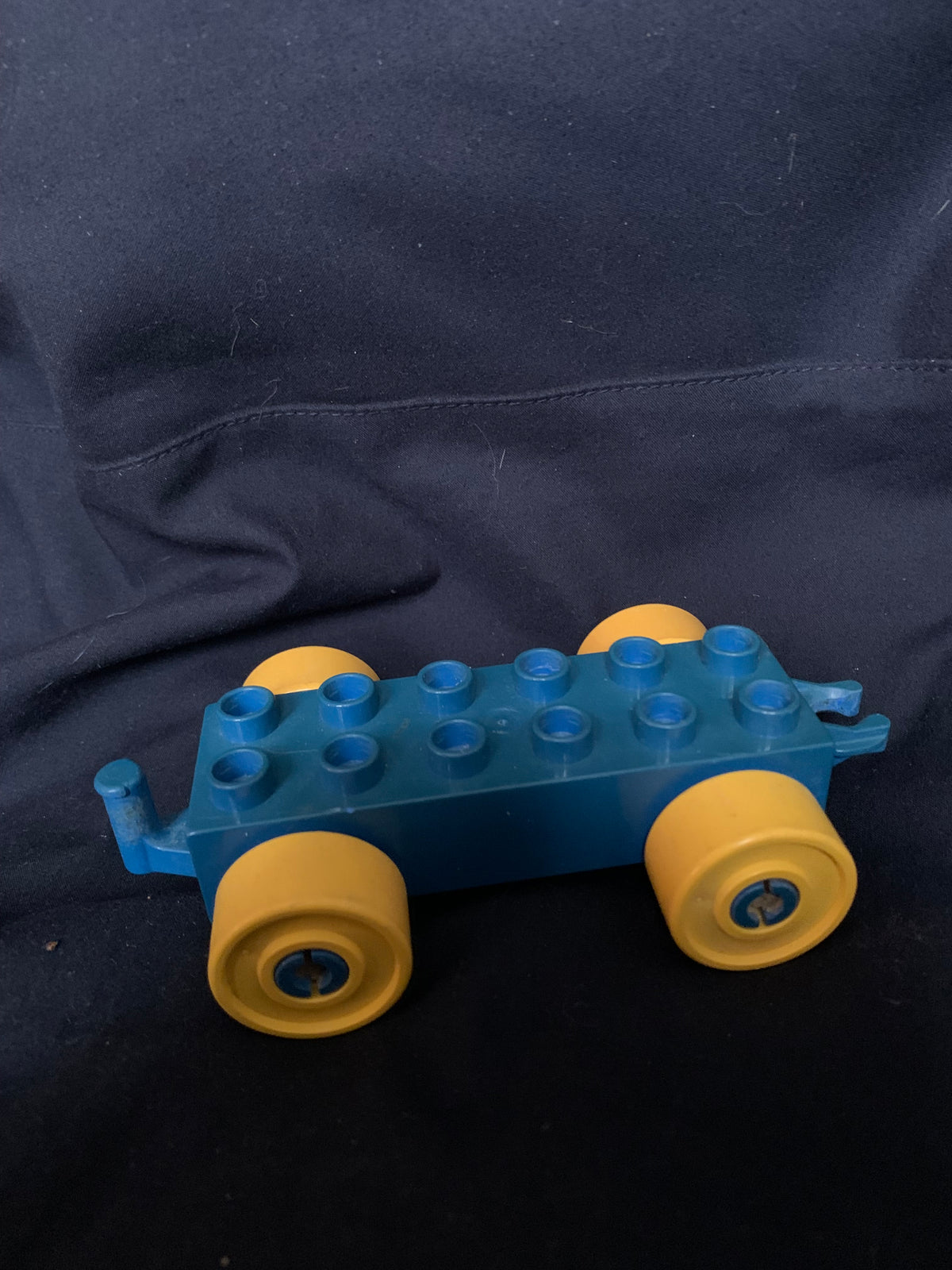 Blue and yellow plastic lego duplo train car with four wheels from toys 001 shown from the back side