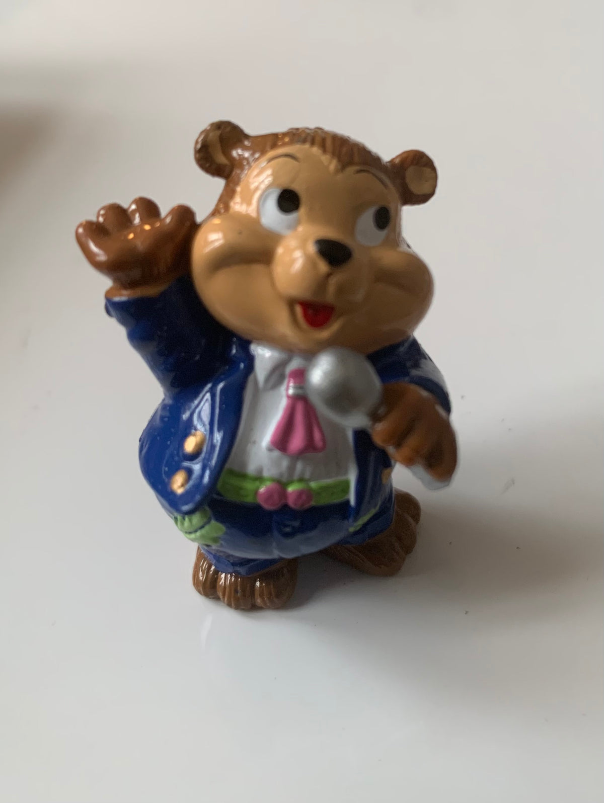 A cheerful brown chipmunk figurine in a glossy blue suit with gold buttons holding a silver microphone for display