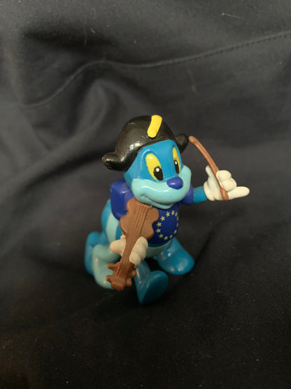 Blue cartoon frog figurine wearing black tricorn hat with yellow stripe holding brown stringed instrument and bow toy