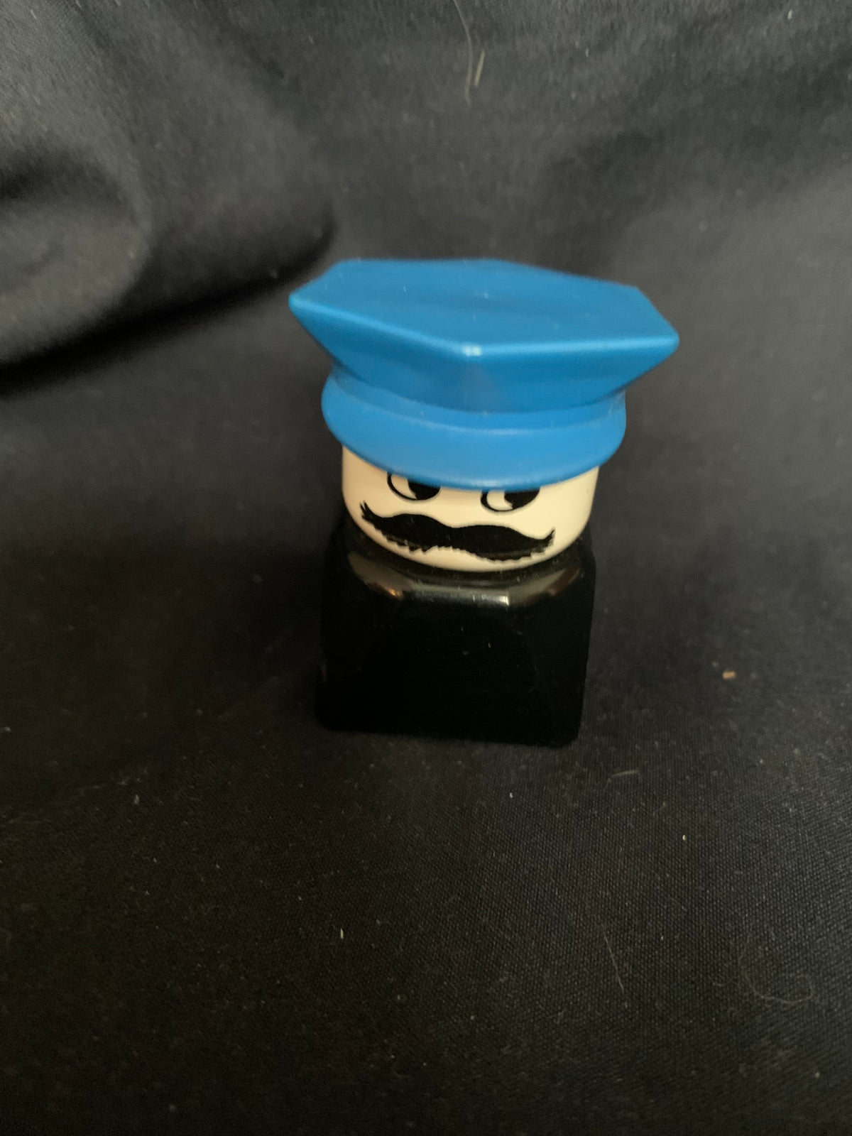 Blue plastic lego minifigure head with black mustache and eyes wearing a blue cap from toys 001 collection