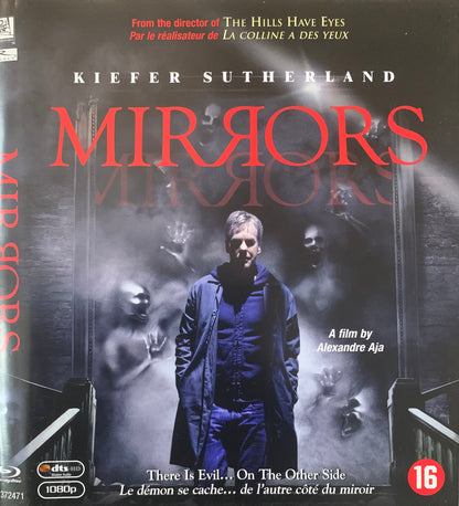 Blu-ray disc cover for the horror film mirrors featuring kiefer sutherland in a dark blue coat with smoky backdrop