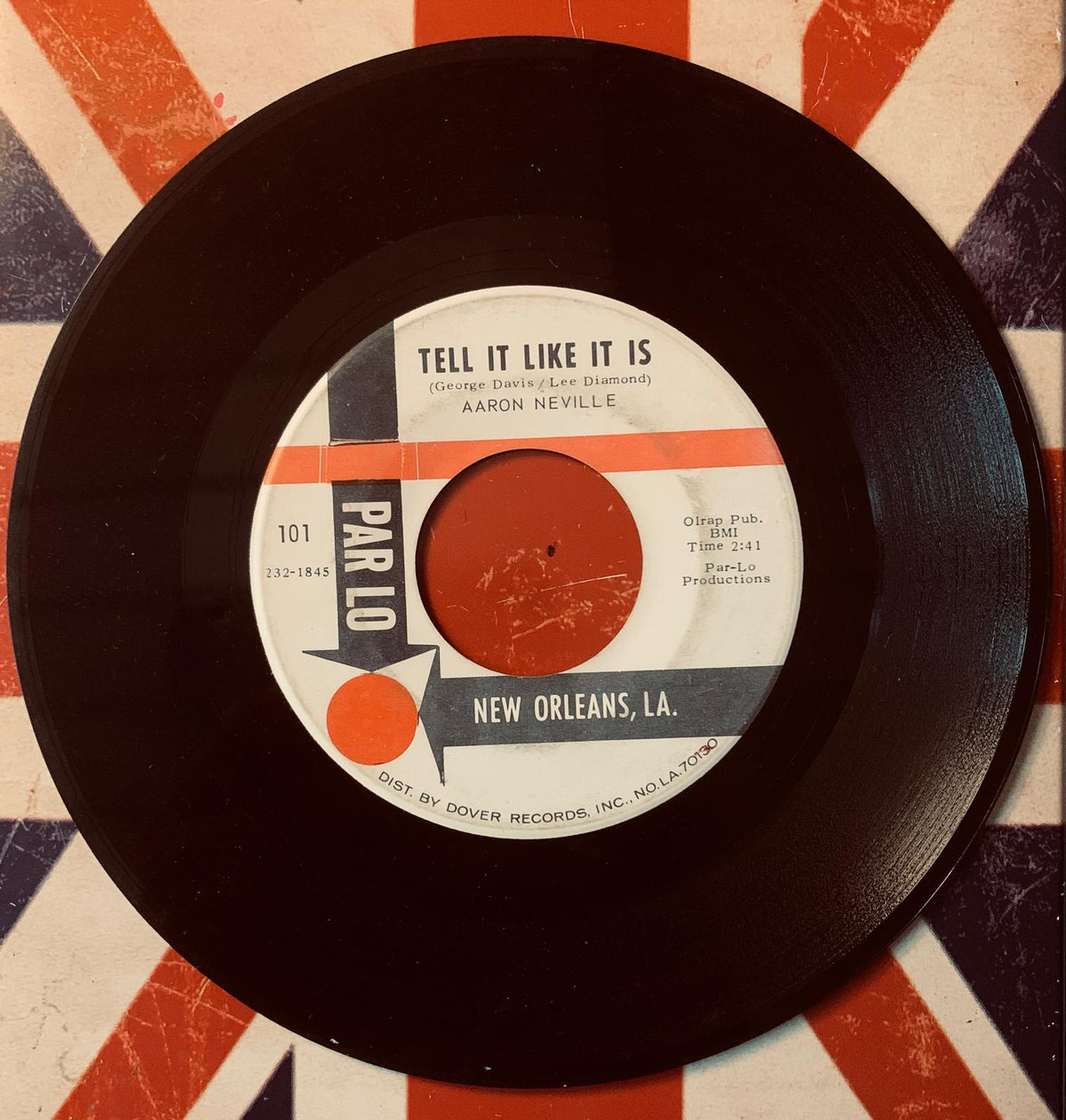 Black vinyl record with white label and orange and gray accents featuring aaron neville song tell it like it is on parlo records