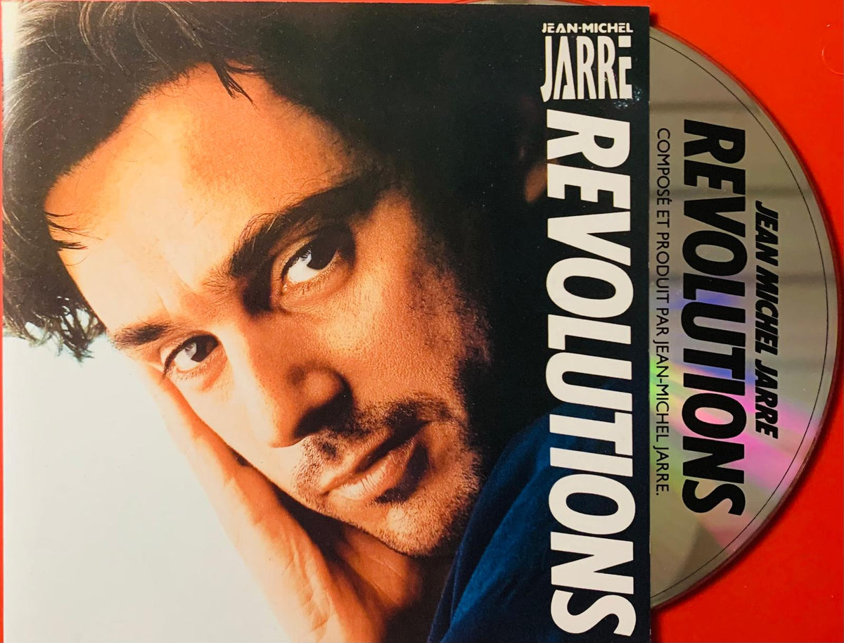 Close-up portrait of jean-michel jarre with dark hair intense eyes on the revolutions original cd cover white background