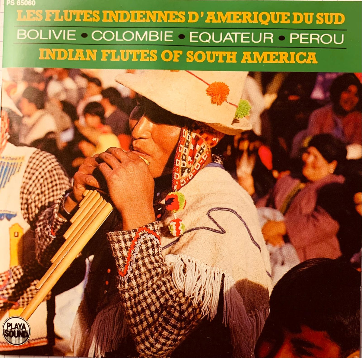 A wooden pan flute with multiple tubes held by a person in traditional south american attire from various artists cd