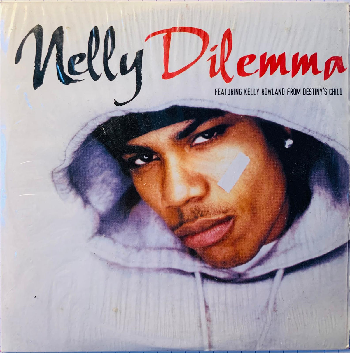 Album cover of the original cd dilemma by nelly featuring a portrait of the artist in a light gray hoodie with white face paint