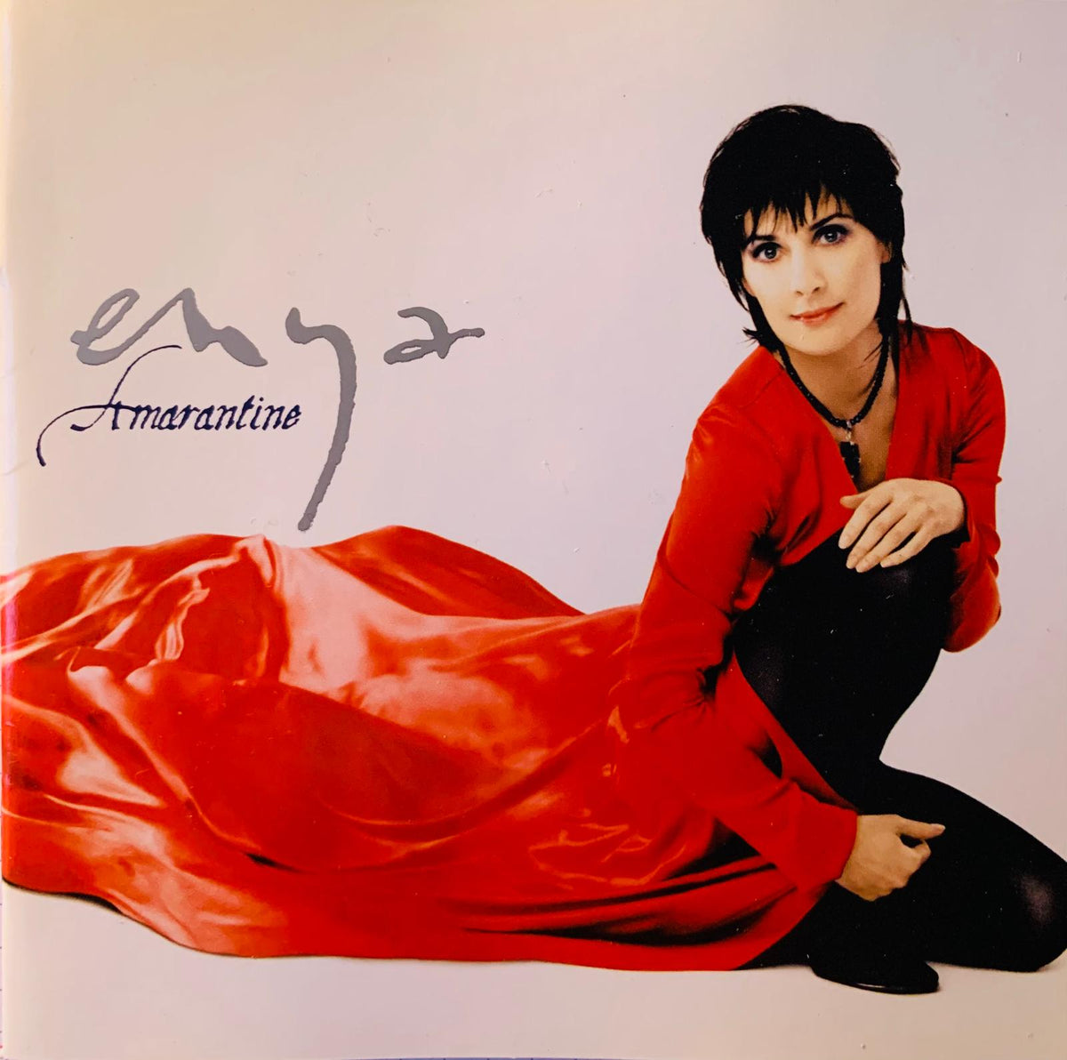 A woman wearing a vibrant red satin gown with long sleeves and black leggings for Enya Amarantine original CD product