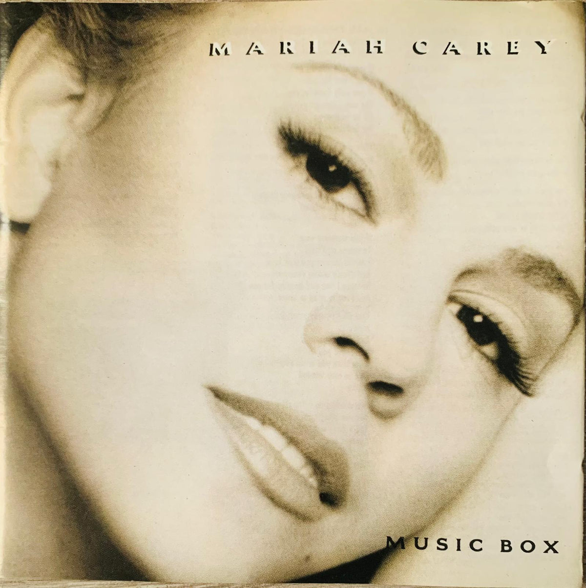 Sepia toned mariah carey music box album cover with close up portrait and black serif title at top and bottom