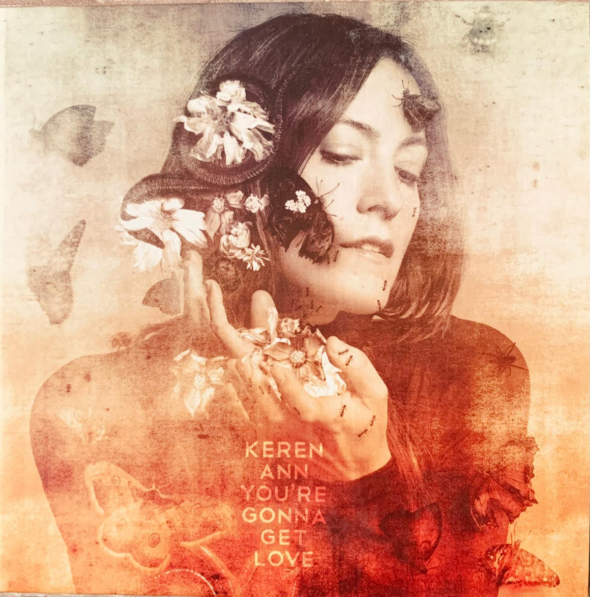 A sepia-toned album cover of keren ann’s original cd featuring a woman with white flowers and butterflies on aged paper