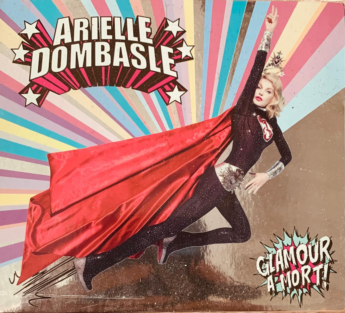 Arielle Dombasle in a black sparkly bodysuit with red satin cape and silver accessories on rainbow background for original CD