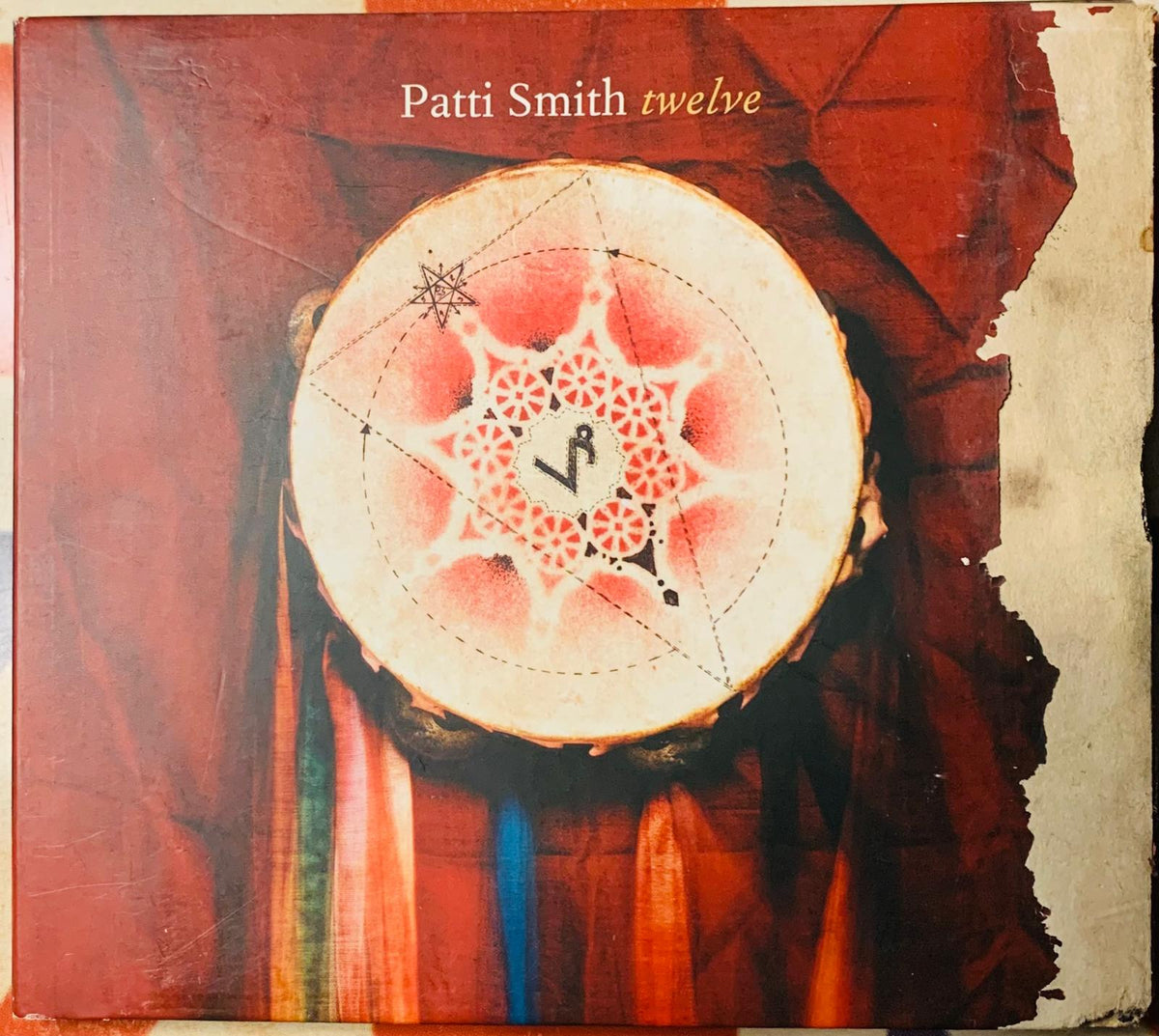 The album cover for patti smith twelve 2007 original cd features a circular drumhead with red and white geometric patterns