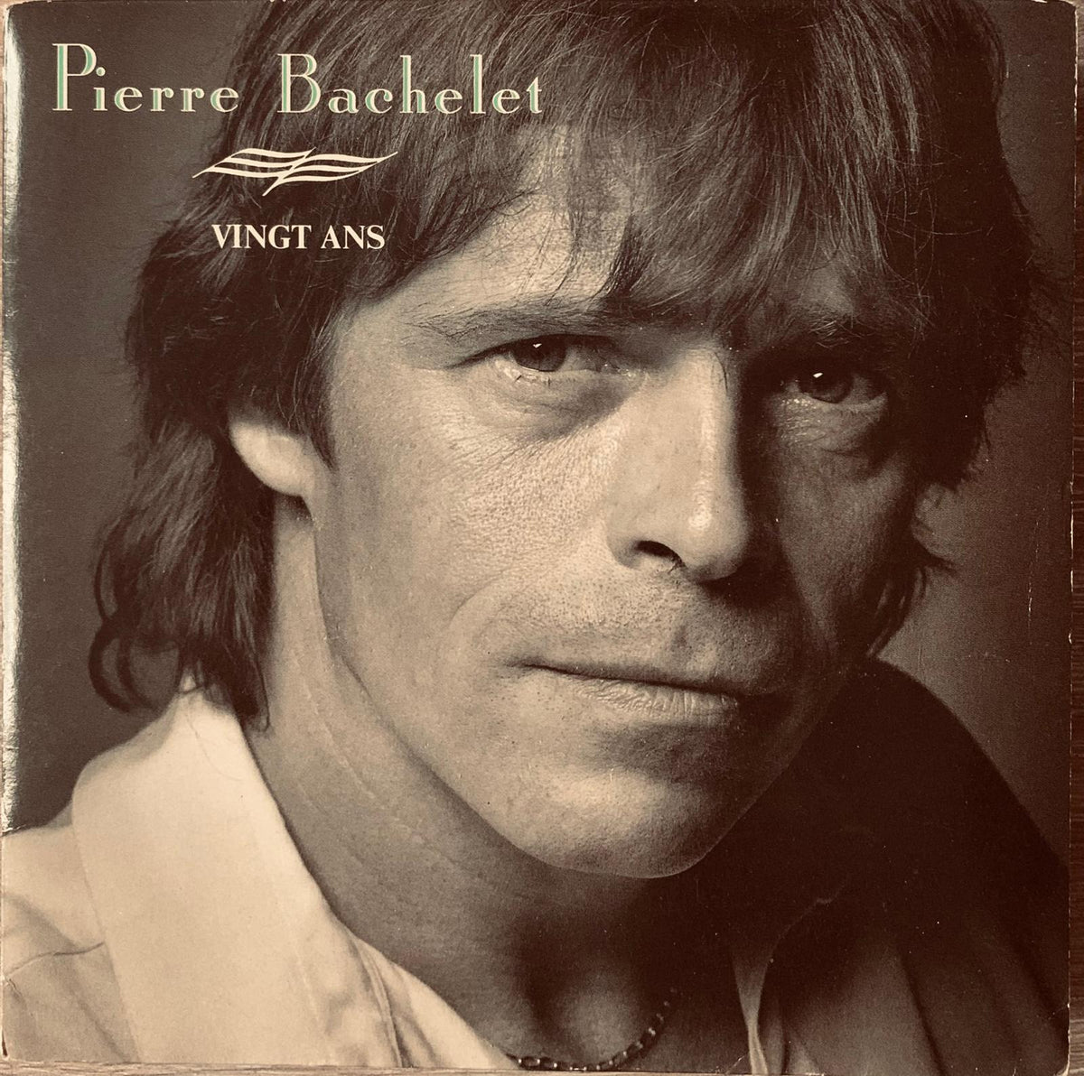 Sepia-toned vinyl album cover of pierre bachelet featuring the title vingt ans in serif font from the 1980s