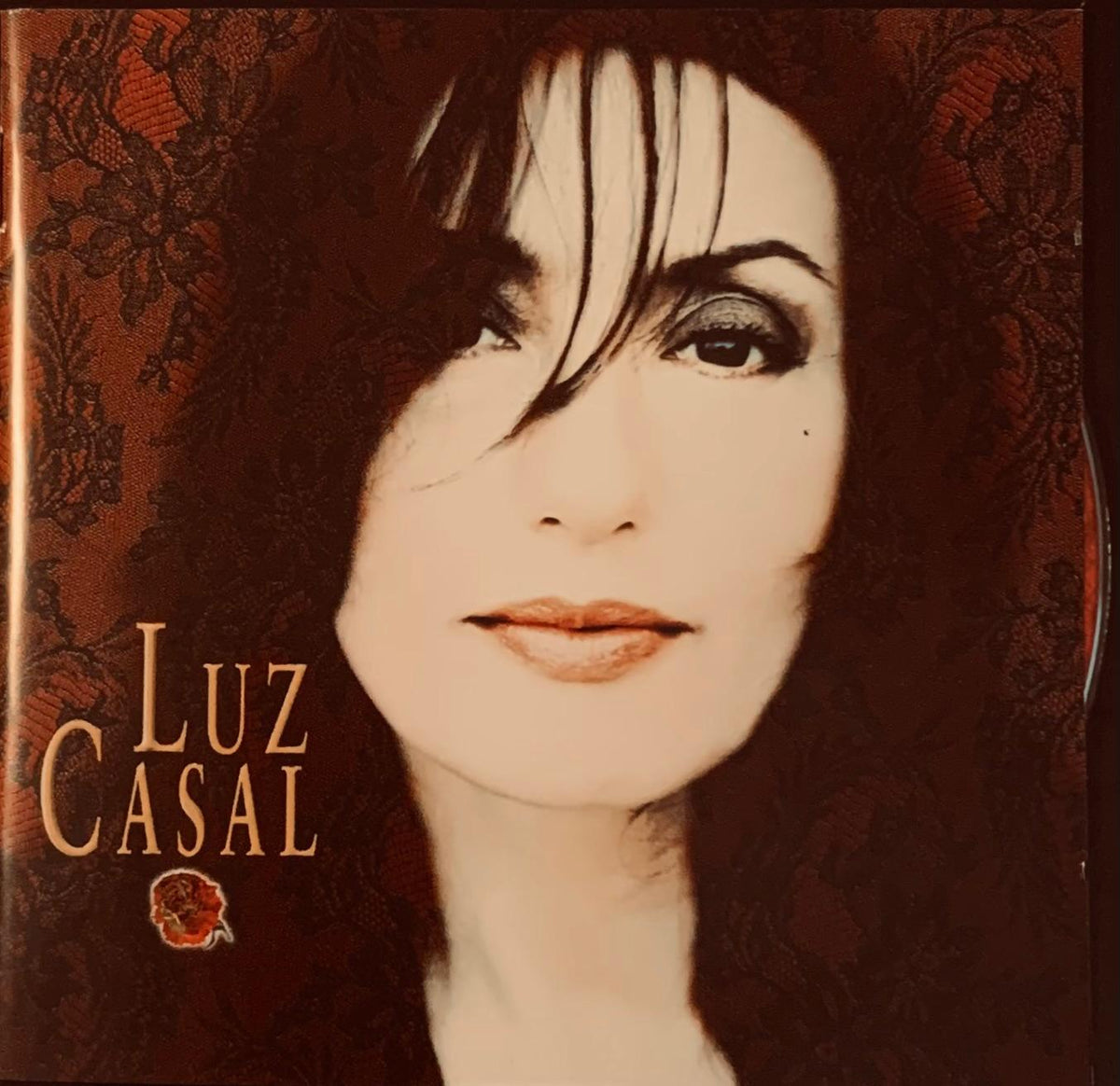 Luz Casal original CD album cover featuring a close-up portrait with dark hair and warm-toned makeup on lace background