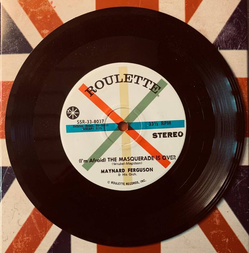 Black vinyl 7 inch record with white label and colorful stripes featuring the masquerade is over by maynard ferguson