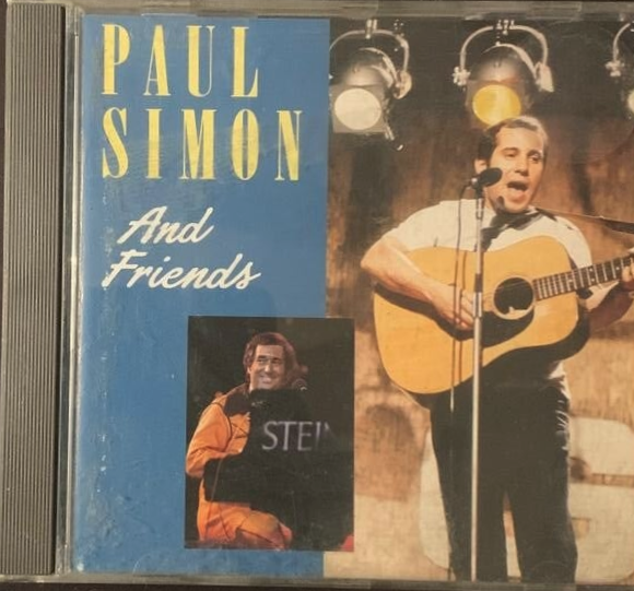 Paul Simon and Friends CD album cover with blue background yellow text and Paul Simon playing guitar on stage