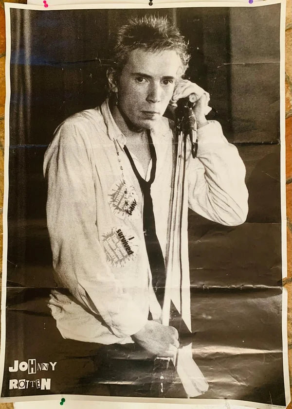 Black and white vintage poster of johnny rotten in a white embroidered shirt holding a microphone for rock new wave fans