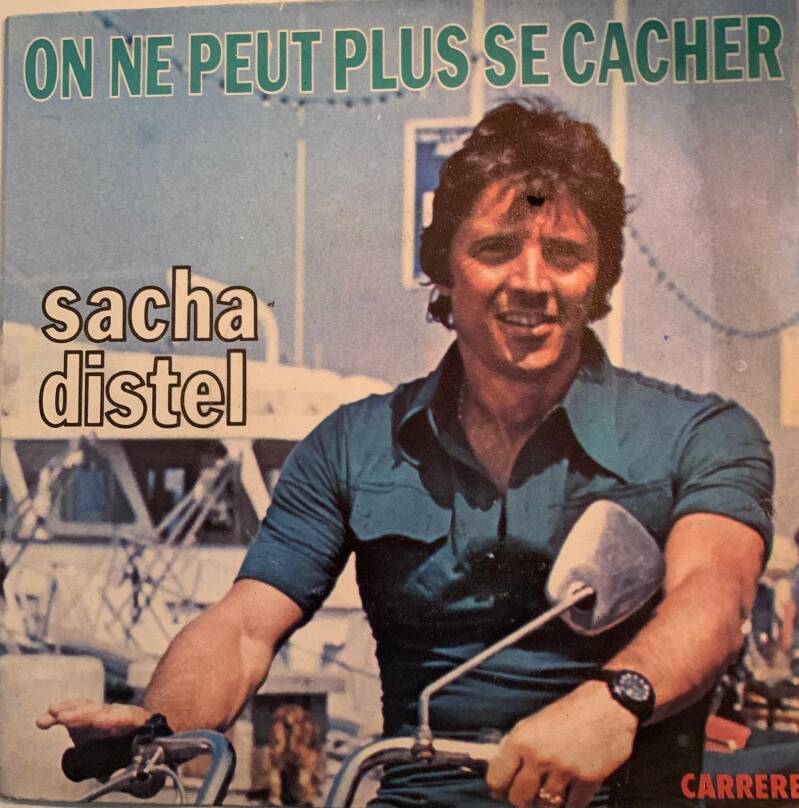 Sacha Distel on the cover of his 1970s french album on ne peut plus se cacher wearing teal shirt on motorcycle